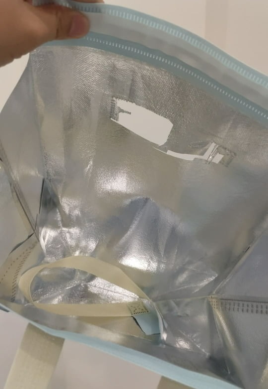 A close-up of reinforced cross-stitching on a bag handle versus a simple heat-sealed seam